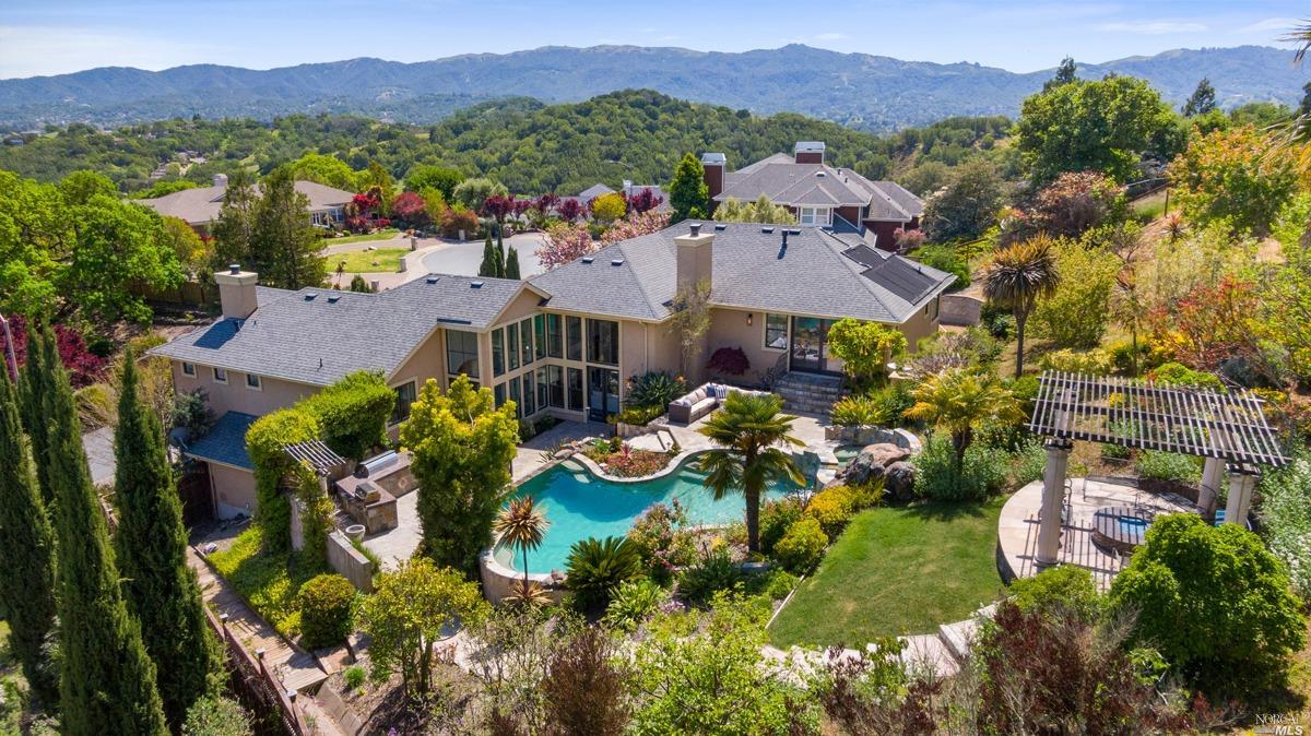 This mediterranean-inspired estate is an entertainer's dream. Custom designed and built on nearly 1.46 acres, with sweeping views & a one-of-a-kind backyard, this home is designed for indoor/outdoor living.   Located in one of the most desirable, private neighborhoods in Novato, this 4BR/3.5BA home was built in 2007.  A dramatic entry with soaring ceilings welcomes you into a foyer, opening up to the living and dining areas, the heart of this house, offering views, high-end appliances, a breakfast nook, & natural light. The ensuite bedroom on the entry level offers convenience.   The manicured resort-like backyard features a spectacular pool with waterfall, jacuzzi, outdoor fireplace, built-in BBQ & outdoor kitchen & year-round blooms of many species.  A beautiful primary suite is complete with a luxurious spa-like bath and sliding glass door with direct access to the swimming pool, jacuzzi, & outdoor kitchen. Upstairs you will find 2 additional large bedrooms, & a sizable laundry room. A three-car garage & a large driveway make the home even more ideal for entertaining.   The estate sits on an elevated hillside lot close to Mt. Burdell, open space preserve with endless hiking and biking options nearby. You will fall in love with this one-of-a-kind, forever home.
