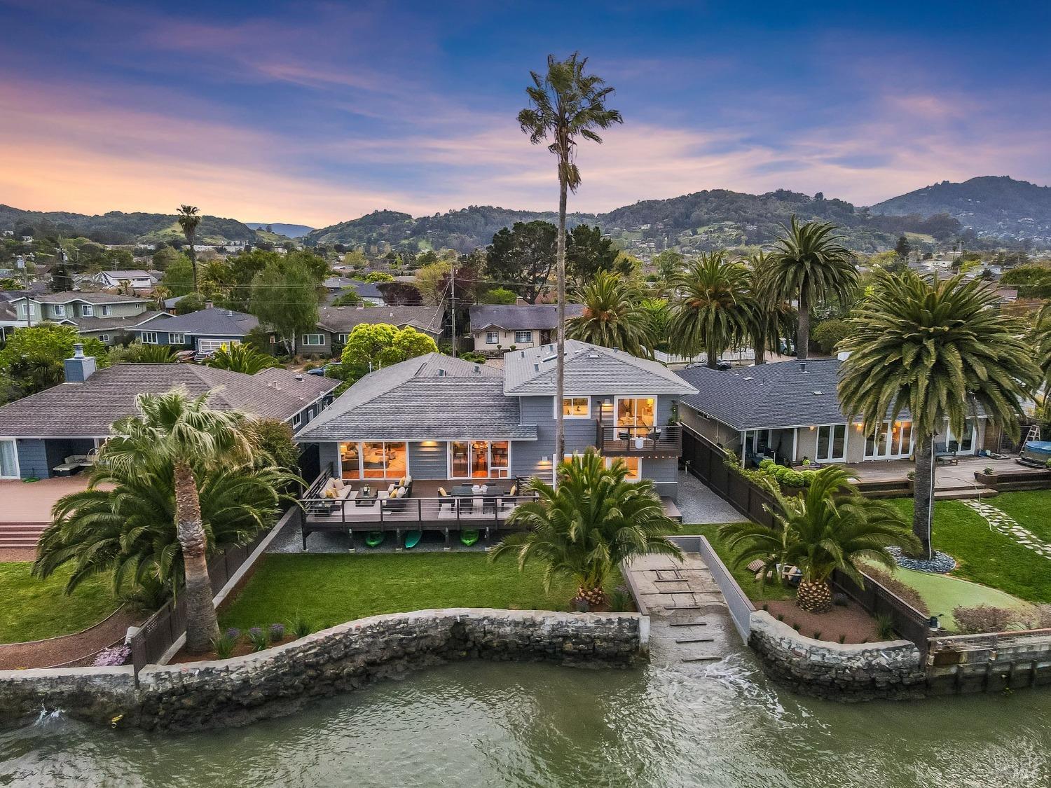 Rarely available, updated and expanded waterfront home in Corte Madera's coveted Mariner Cove neighborhood. World class water views and a private SF Bay boat ramp for kayaking, boating and paddle boarding from your backyard. This stunning home features beautiful wood floors, an updated open kitchen with water views seamlessly flowing to dining and living rooms, and connecting to the backyard via sliding glass doors. The flexible floor plan offers 3 bedrooms on the lower level, including a spacious en suite bedroom (was previously 2 br's, could be again). The 4th bedroom is a legal ADU and is located upstairs with interior access and its own private exterior entry as well. A full kitchen, bath and laundry make it great as an au pair suite, granny/ in-law unit, rental or work from home space as desired. Incredible water views from kitchen, living room and balcony. The lush grounds include level lawn, spacious deck, mature palm trees and gardening areas offering fantastic spaces to dine al fresco, bbq with friends and family or just enjoy the views of the water and abundant marine and bird life. Excellent school district, just down the block from the highly regarded Cove elementary school. Great SF commute location. This is the good life. Come home to Corte Madera.