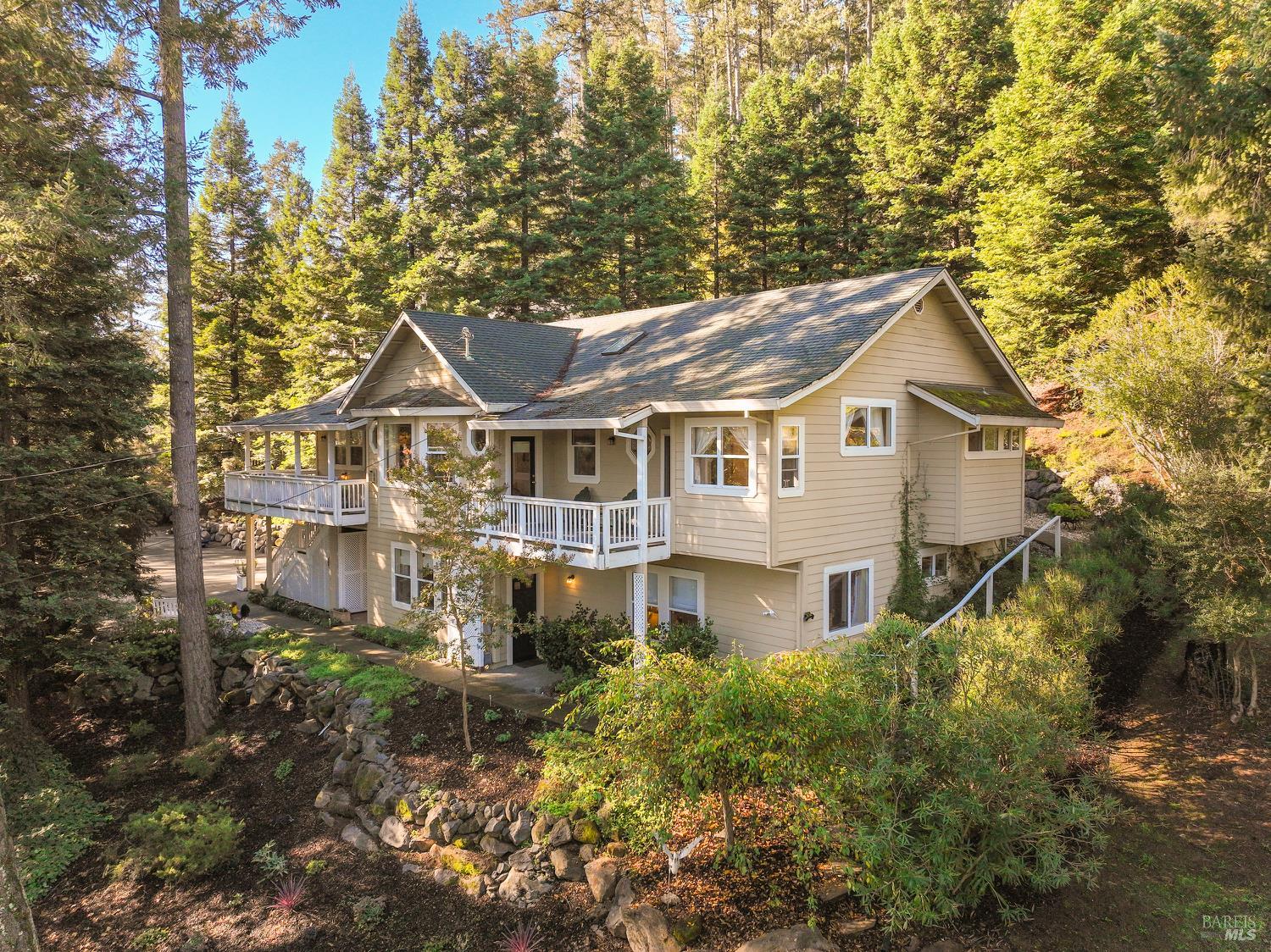 1885  Los Olivos Road  Santa Rosa, California Nestled among towering redwoods at the end of a private drive, this serene Los Olivos retreat blends comfort, style, and modern convenience. With filtered forest views, wraparound decking, skylights, and custom octagonal windows, the home offers a seamless connection to nature. Inside, 10'+/- ceilings enhance bright, open living spaces. The living room features a gas fireplace with marble hearth, and the dining room includes hardwood floors and designer lighting. The kitchen offers stainless steel appliances, double ovens, an island with rinsing sink, and adjacent laundry room with storage and patio access. The sunroom's vaulted ceilings and large windows overlook the lush yard. The primary suite features a bay window, private deck, walk-in closet, and spa-like bath with dual vanities and oversized shower. Two guest bedrooms open to the deck; the guest bath includes a jetted tub. The lower level offers a living area, kitchenette, wine storage, guest suite, and full bath. Central zoned heat & air, hardwood floors, and an oversized three-car garage with workshop complete this private retreat.